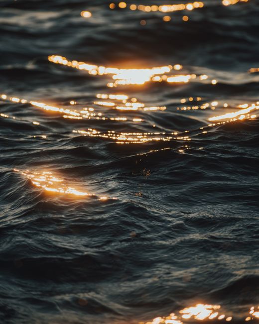 Close-up of ocean waves glowing with golden sunlight reflections during sunset.