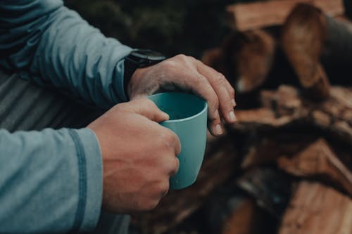 Person in Blue Long Sleeve Shirt Holding Blue Ceramic Mug