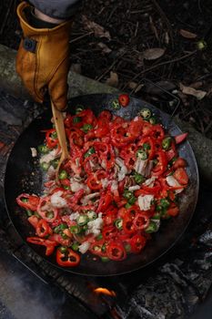 Delicious spicy vegetable stir fry cooked outdoors over open fire, featuring red and green peppers.