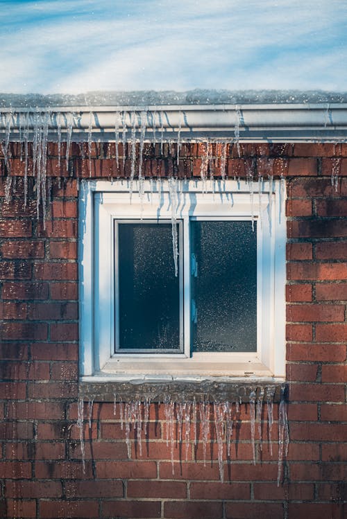 A Brown Brick House with Frozen Water  During Winter