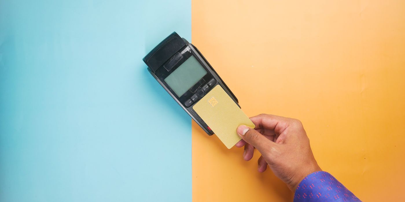 A hand tapping a credit card on a payment terminal at a hotel