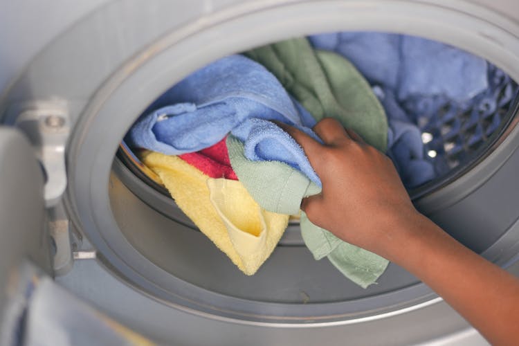 Woman Hand Putting Towels In Washing Machine