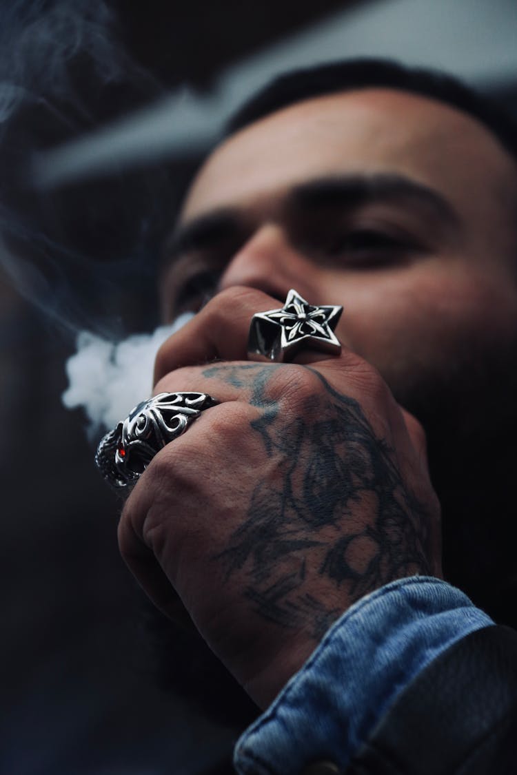 Smoking Man With Tattoo And Rings On Hand