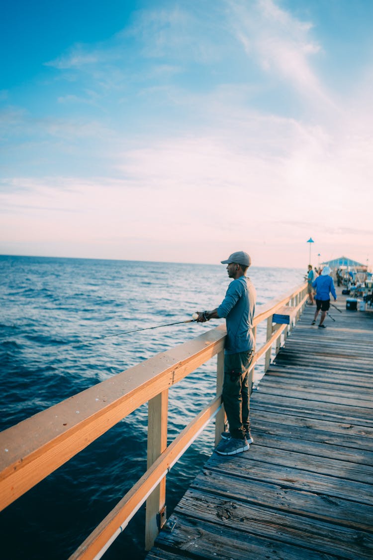 A Man Standing On A Dock While Fishing