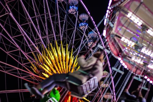 Free Colorful ferris wheel and swing ride capture the exhilarating amusement park atmosphere at night. Stock Photo