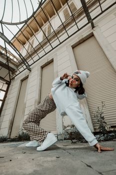 Young woman posing dynamically in urban setting, embracing modern fashion and youth culture.