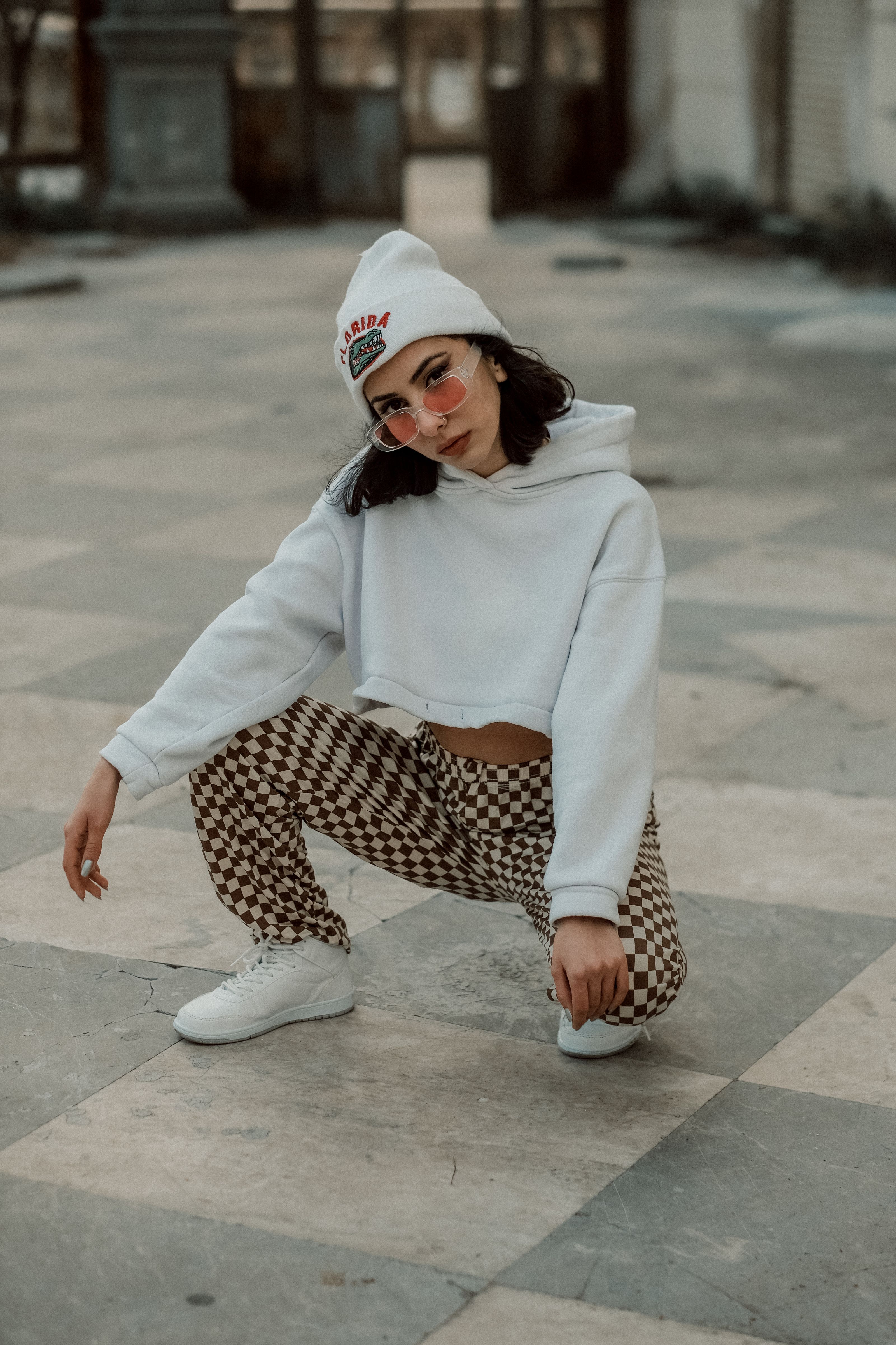 Mulher posando em um traje da moda com touca e calças xadrez.