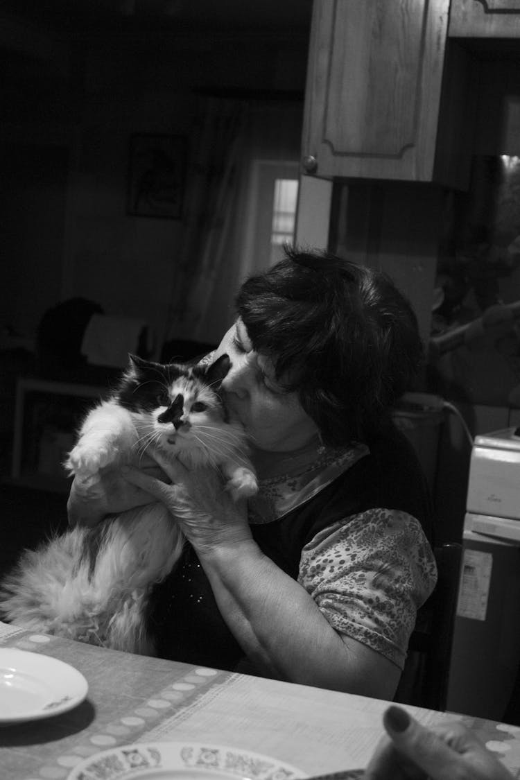 
A Grayscale Of A Woman Kissing Her Cat