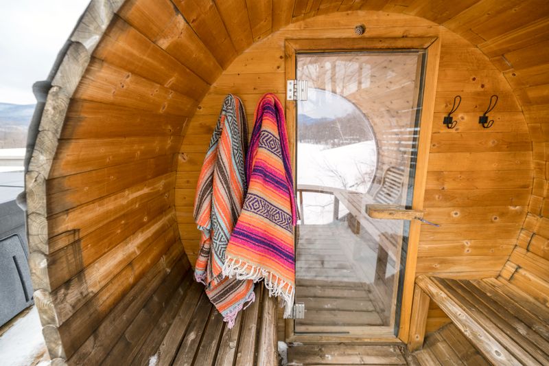 Wooden sauna interior with colorful towels, snowy landscape visible through window