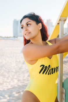 Latina woman enjoying a sunny day at Miami Beach in a stylish yellow swimsuit.