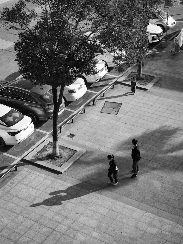 Grayscale Photo Of People Walking On Parking Lot 