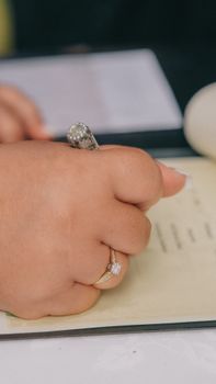 Elegant hand signing a wedding document with a sparkling ring, capturing the moment's essence.