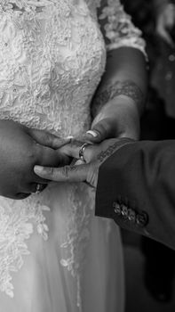 Black and white close-up of a couple exchanging rings at their wedding ceremony.