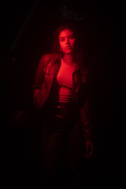 Free Dramatic portrait of a woman in a leather jacket under red lighting. Stock Photo