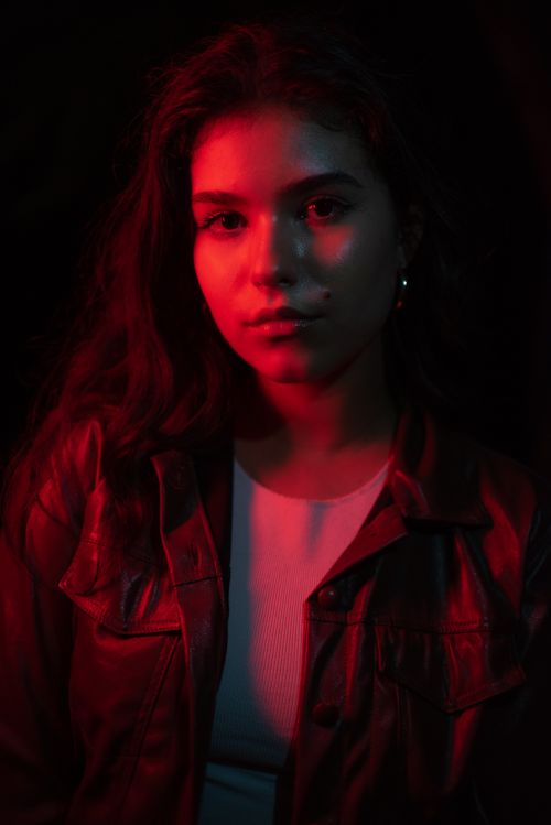 Free Dramatic portrait of a young woman in red lighting, showcasing modern fashion and style. Stock Photo