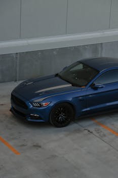 A stylish blue Ford Mustang sportscar parked in an urban setting, showcasing its sleek design.