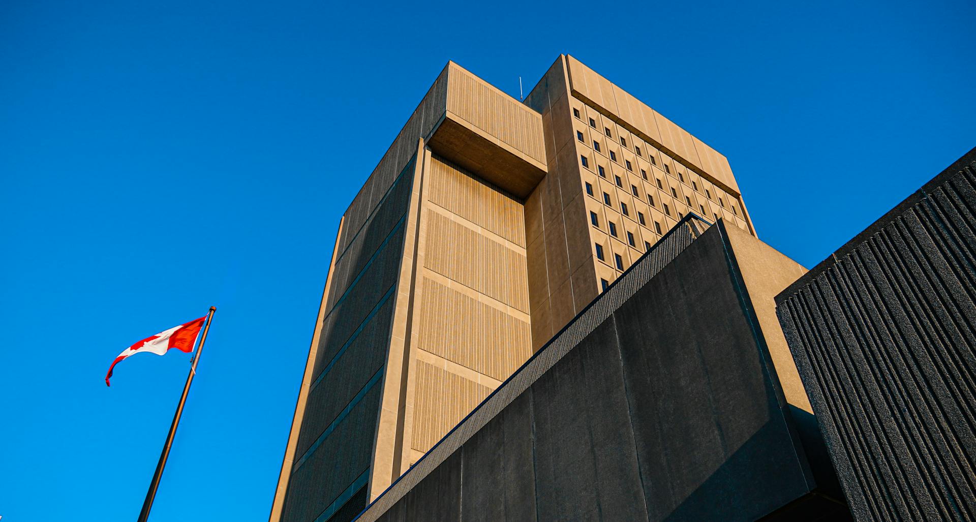 Low-angle shot of modern courthouse architecture with Canadian flag in London, Ontario.