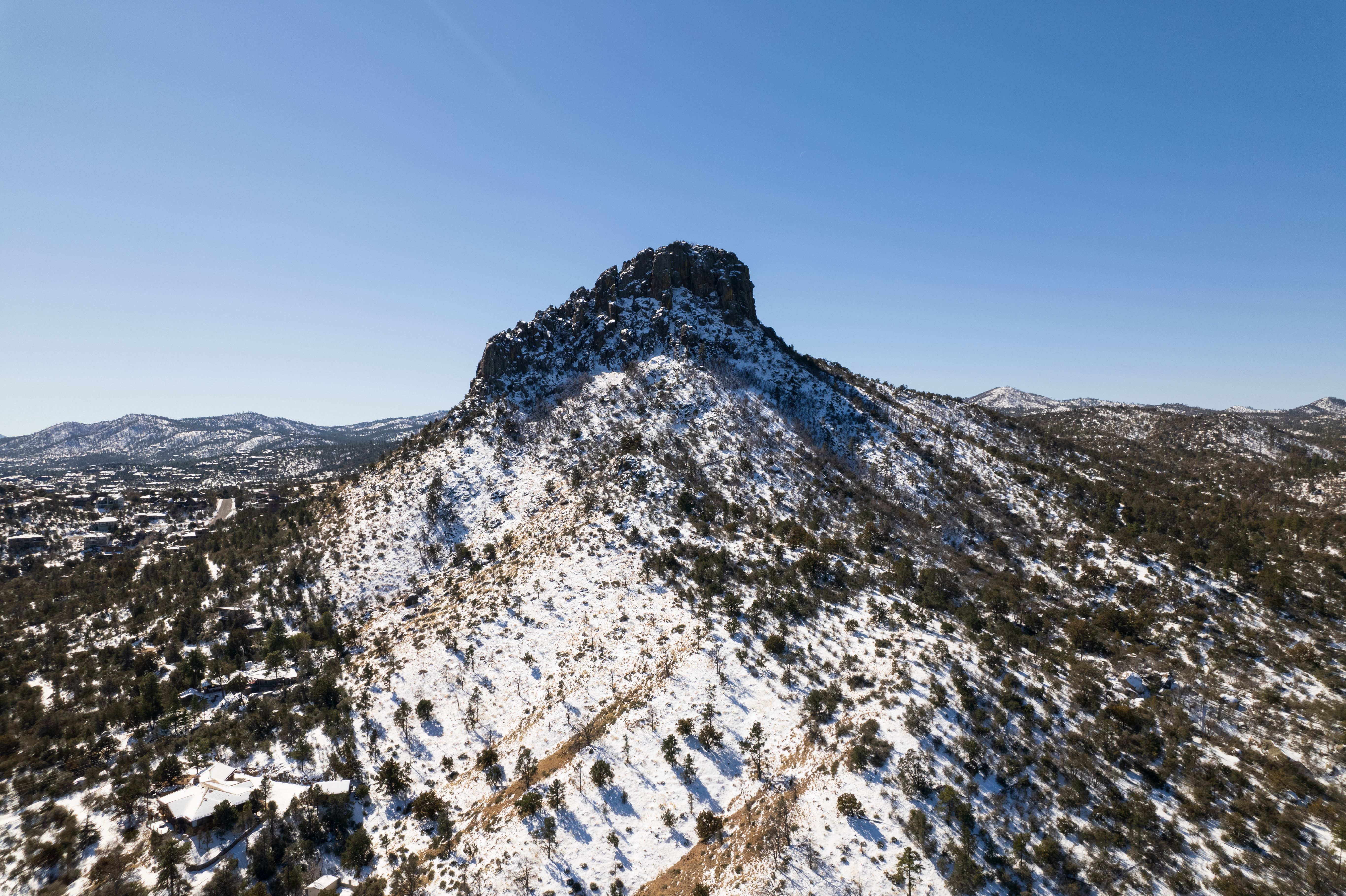 Scenic aerial view of snow-covered Thumb Butte in Arizona's Prescott National Forest.