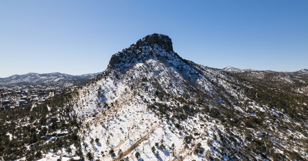 Scenic aerial view of snow-covered Thumb Butte in Arizona's Prescott National Forest.