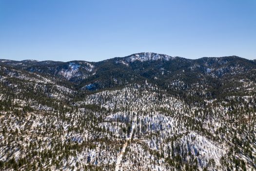Stunning aerial view of a snow-covered mountainous landscape with dense woodland.