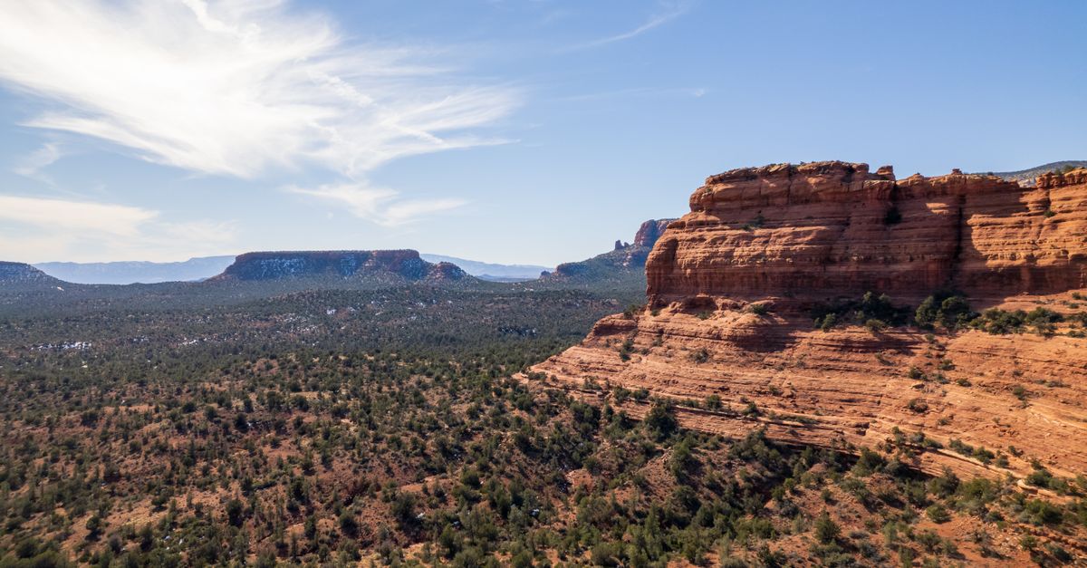 Discover the breathtaking aerial view of Sedona's iconic red rock formations under a clear blue sky.