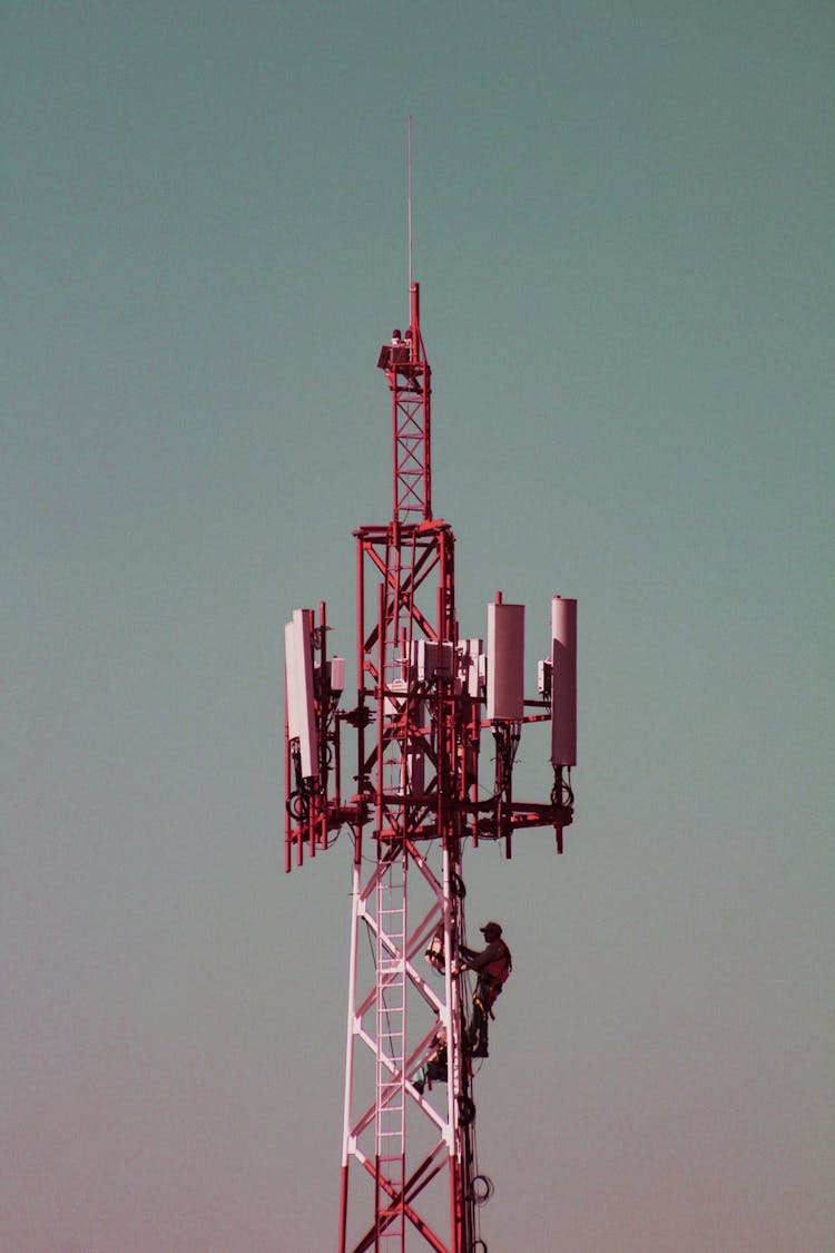 Worker Climbing A Red And White Tower