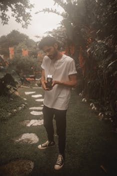 Young man with vintage camera in lush garden, São Paulo.