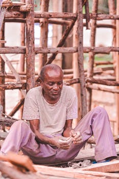 An elderly man works on a wooden construction site, displaying craftsmanship and experience.