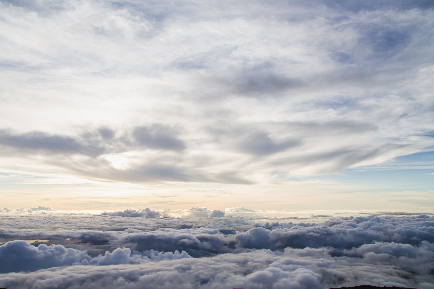 Sunrise light spreading over the cloud layer below the summit of Haleakalā