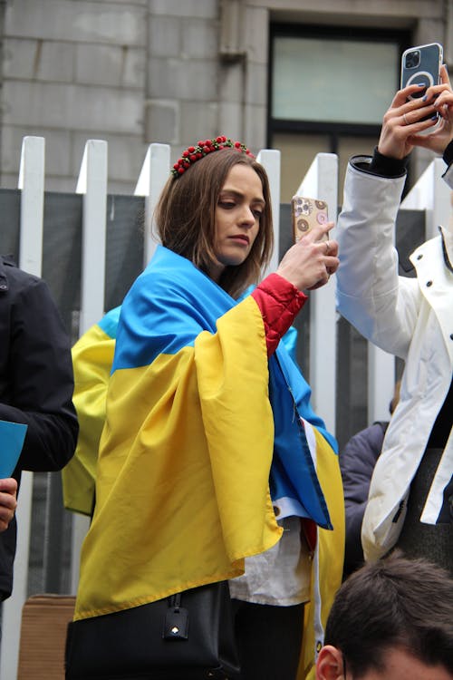 Woman Covered With Ukraine Flag Holding a Phone 