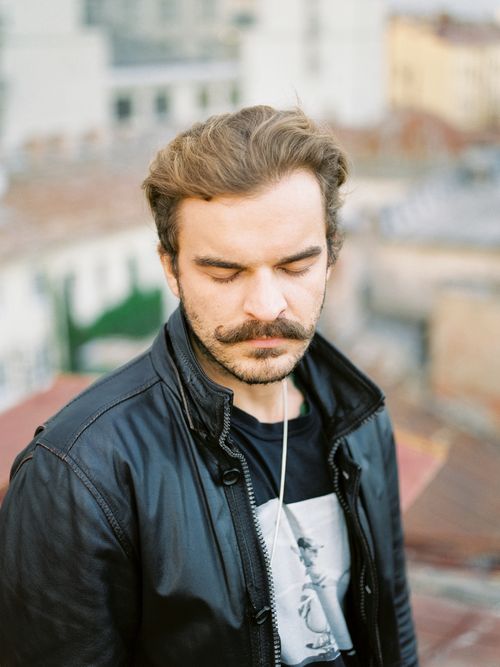 Free A thoughtful portrait of a man with eyes closed wearing a leather jacket outdoors in a city. Stock Photo
