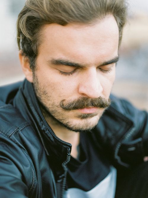 Free Close-up portrait of a man with eyes closed and distinctive moustache wearing a leather jacket. Stock Photo