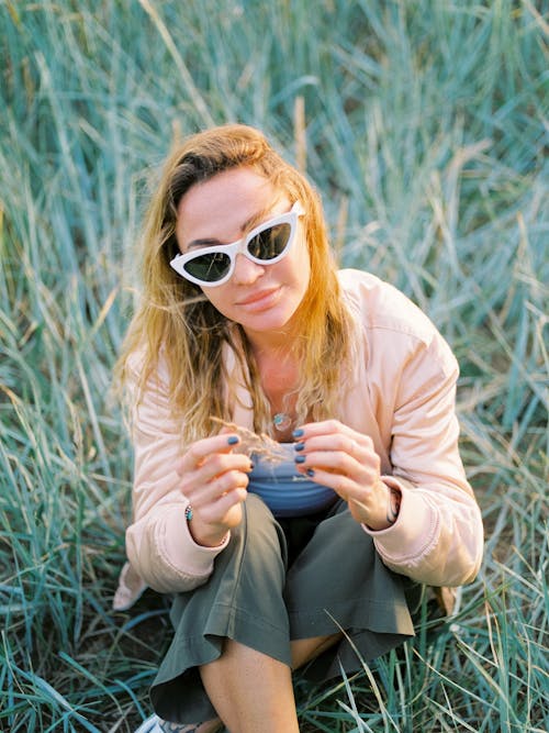 A Woman Wearing Sunglasses Sitting on the Grass 