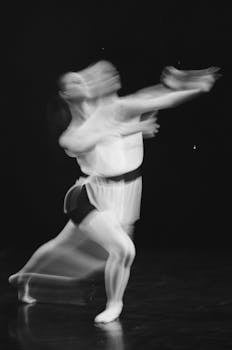 Artistic black and white photo capturing a dancer's motion blur during a ballet rehearsal.