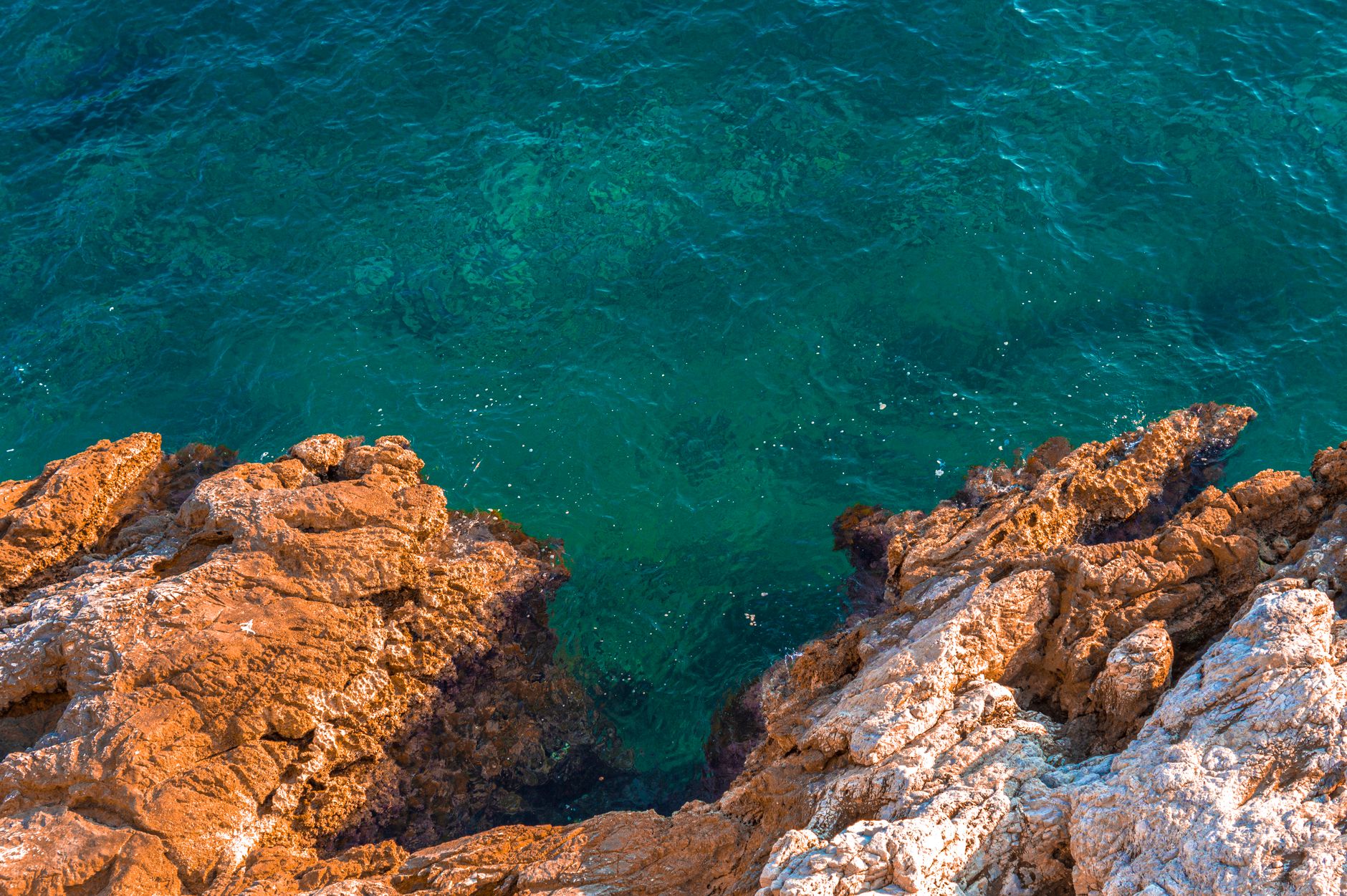 Clear turquoise water over rocks on the Cyprus coast on a bright day