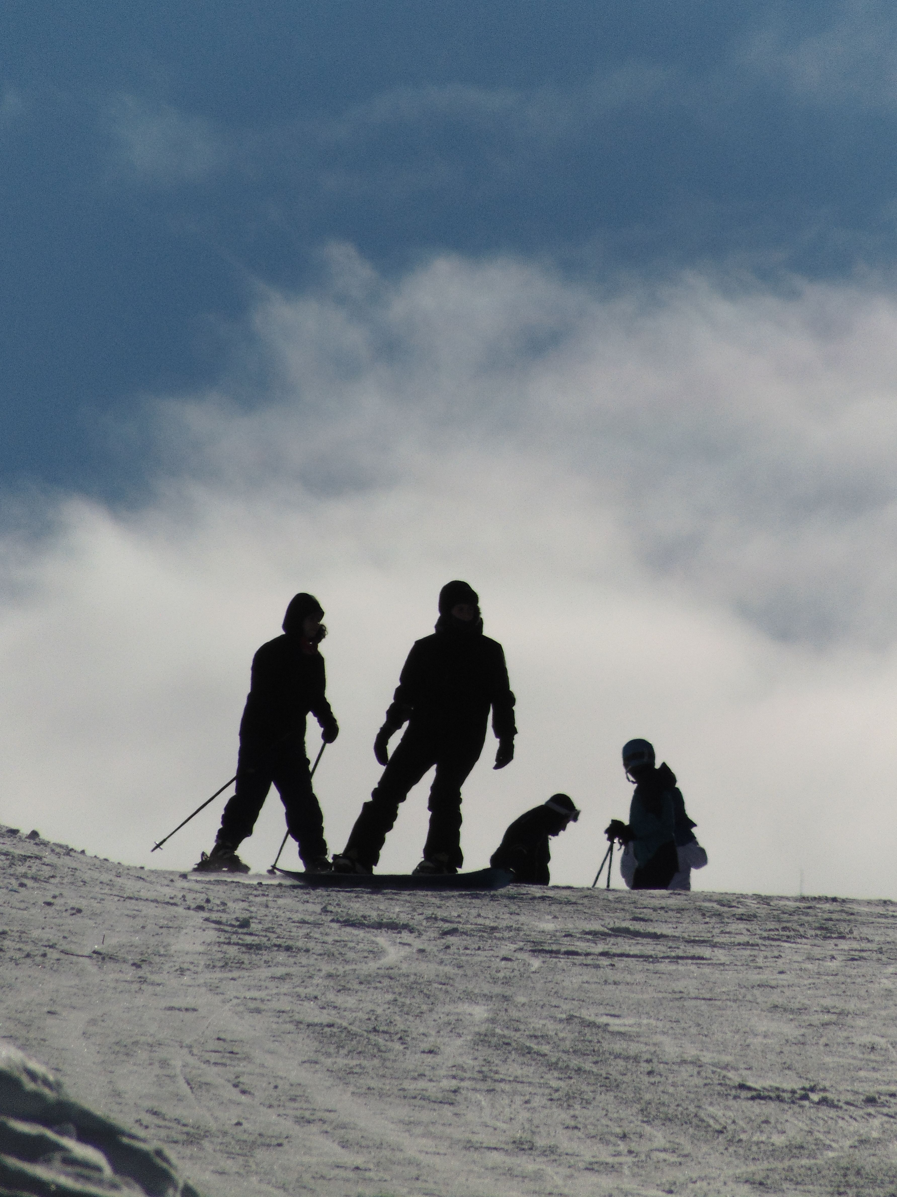 Silhouetted skiers enjoying a winter day on a snowy mountain in Kars, Türkiye.