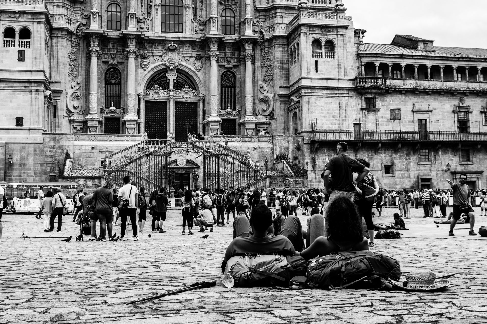 Monochrome scene of pilgrims resting near Santiago de Compostela Cathedral in Spain.