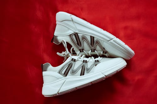 Free White Athletic Shoes on Red Textile Stock Photo