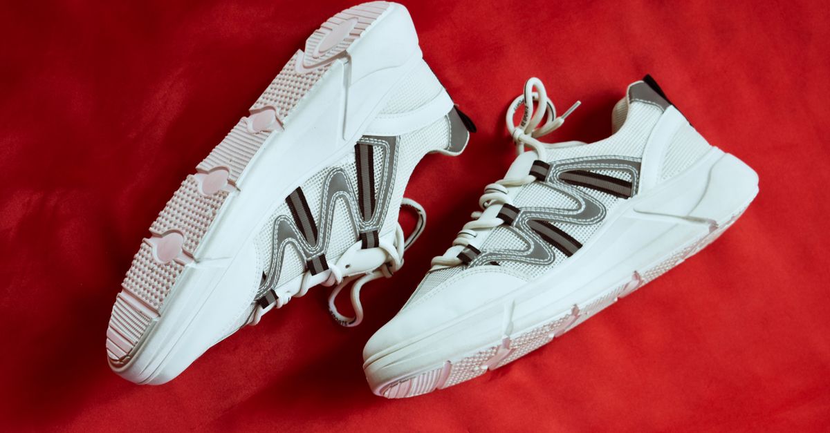 Stylish white sneakers showcased against a vibrant red backdrop, emphasizing contemporary design.