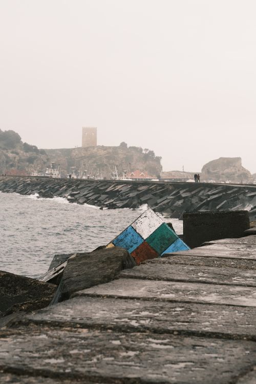 Free Overcast seascape with a colorful ledge on a rocky coastline under cloudy skies. Stock Photo