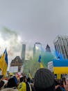 Group of People on Protest With Flags Near High Rise Buildings