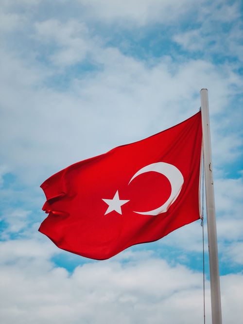 Free The national flag of Turkey waving proudly on a flagpole against a clear blue sky. Stock Photo