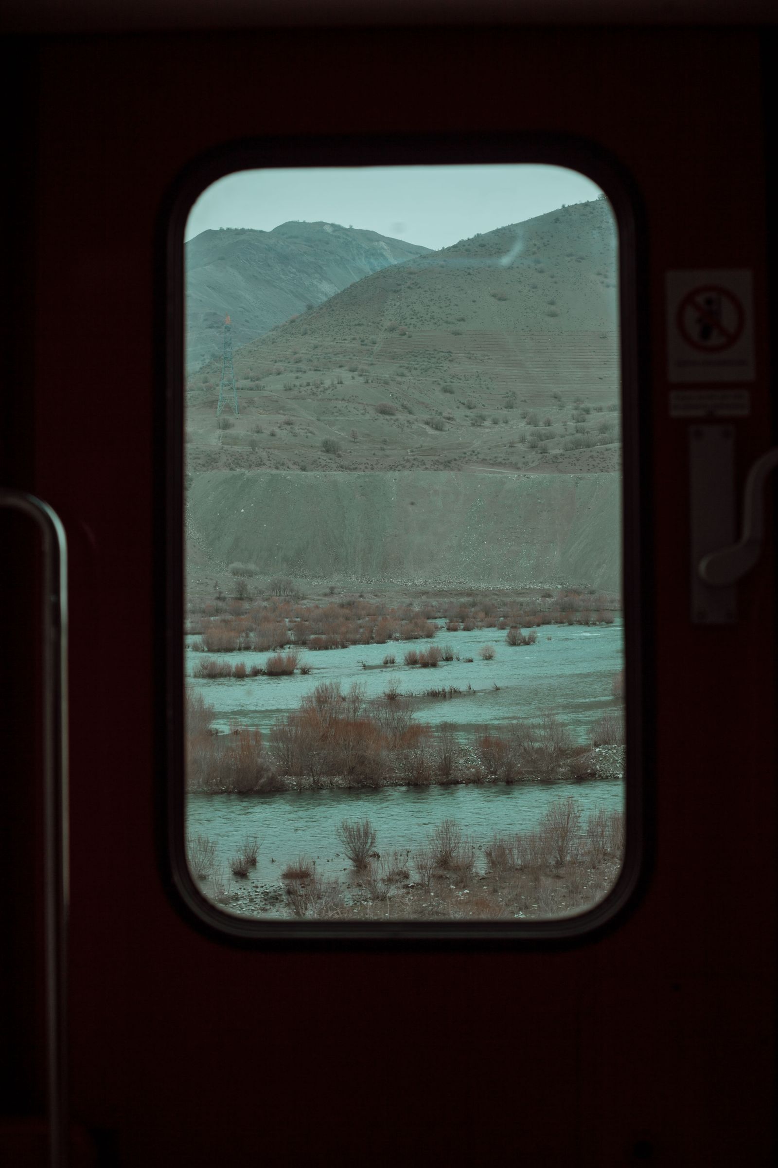 Mountain and river scenery viewed from a train window