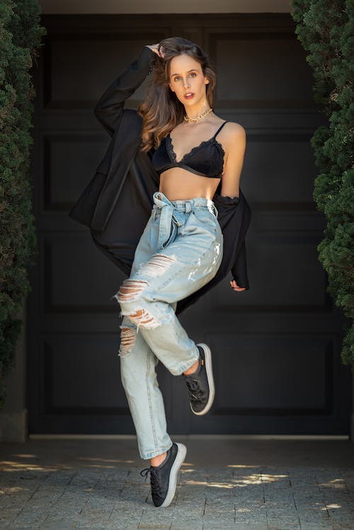 Woman Wearing Bra and Ripped Jeans in front of Building Entrance