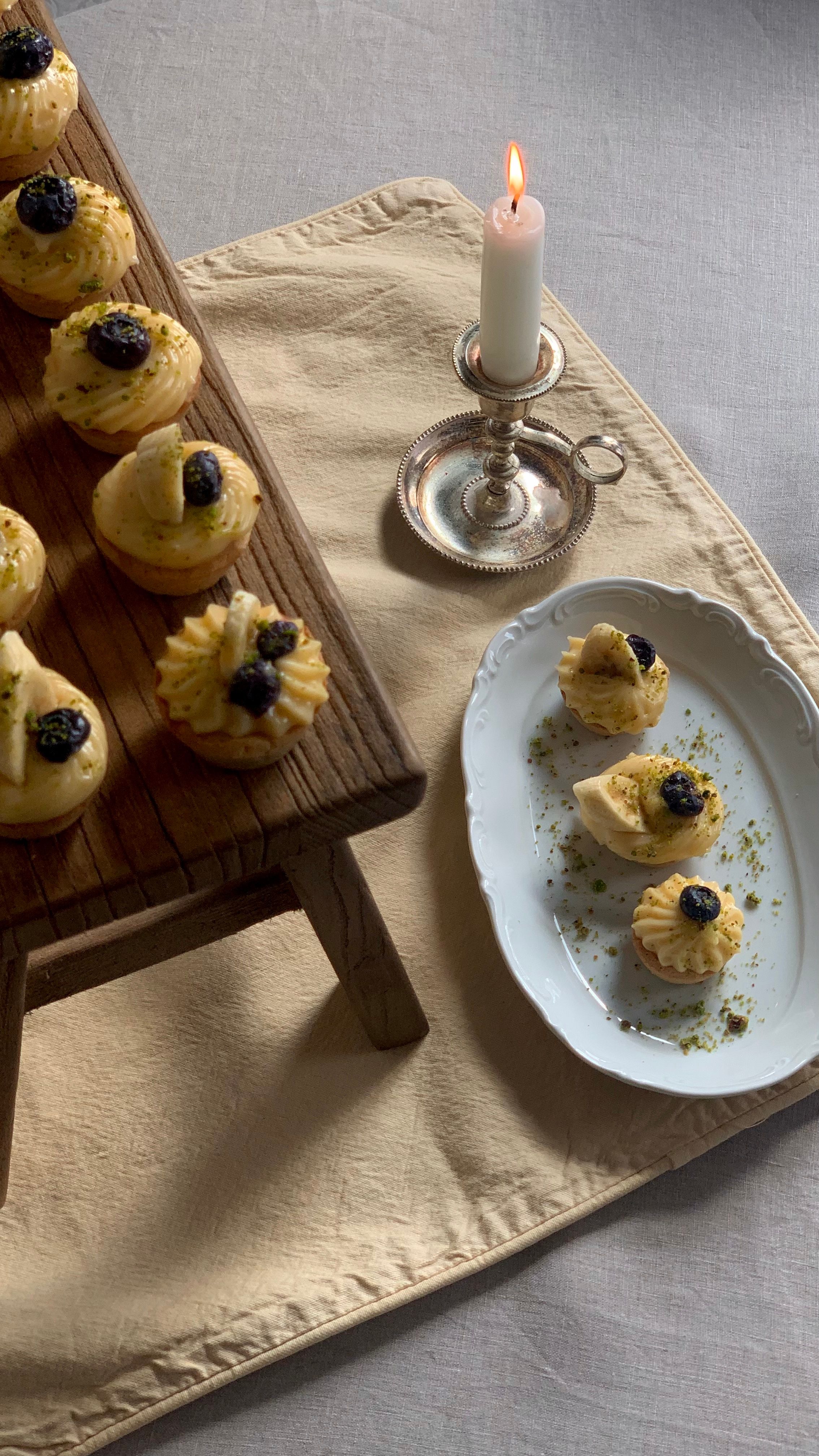 Delicate pastries with blackberries and custard on wooden and ceramic platters under candlelight.