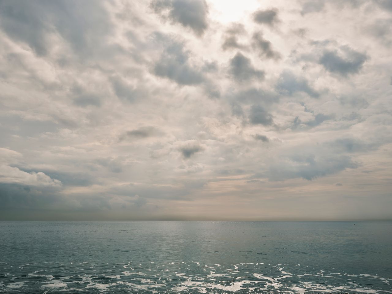 peaceful view of the ocean under an overcast cloudy sky creating a tra