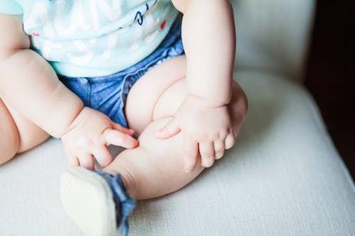 Free Baby Wearing Green Shirt and Blue Shorts Sitting on Gray Chair Stock Photo