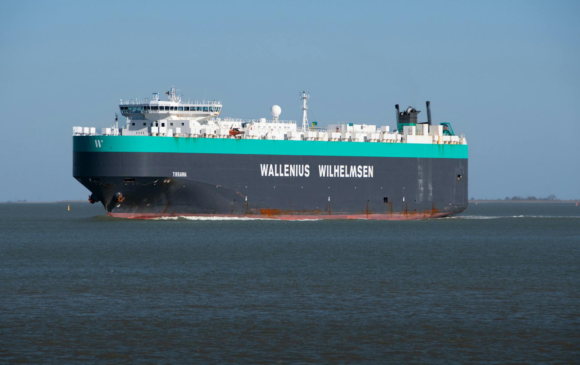 Majestic cargo ship sailing on the open sea under a clear sky, showcasing maritime transportation.
