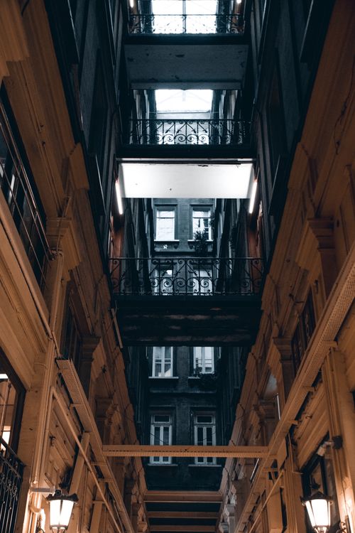 Free Dramatic, symmetrical view of an indoor passage with balconies and lampposts. Stock Photo