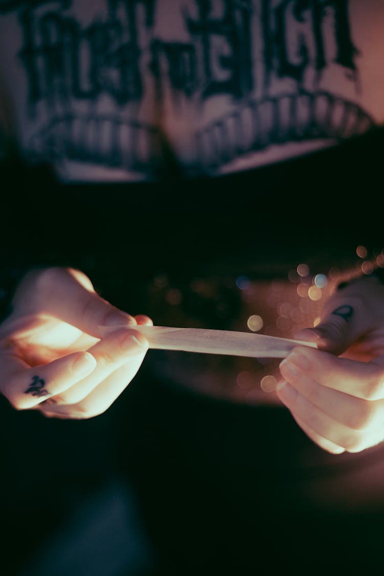 A Tattooed Person Holding A Rolling Paper